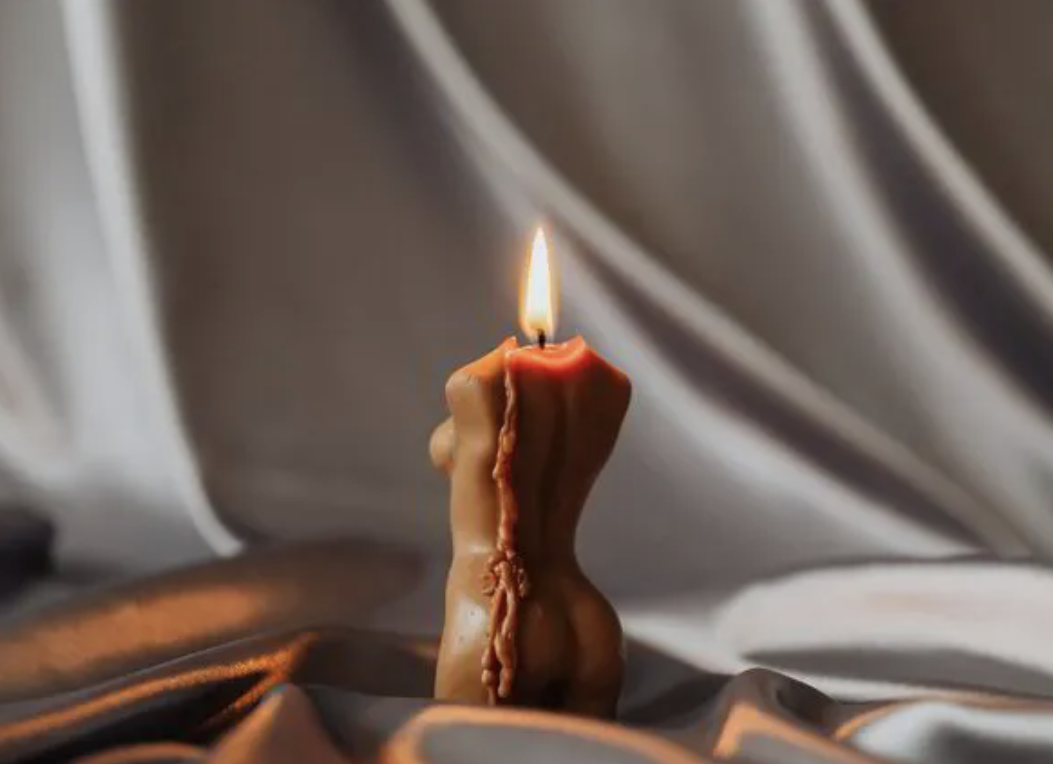 A lit candle resting on silk